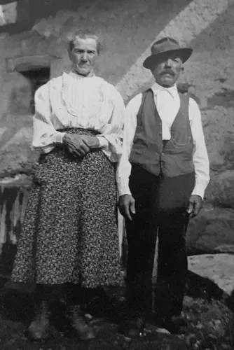 Photo de famille ancienne : un couple devant une maison de pierre en Vallée d’Aoste