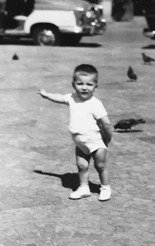 Photo de famille : un petit garçon sur une place, entouré de pigeons